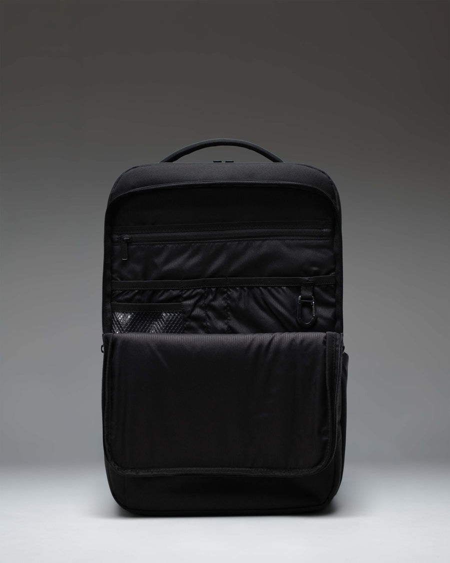 Herschel Supply Co. black Kaslo Backpack Tech shown from the side, emphasizing its sleek profile, padded shoulder straps, and mesh water bottle pocket.