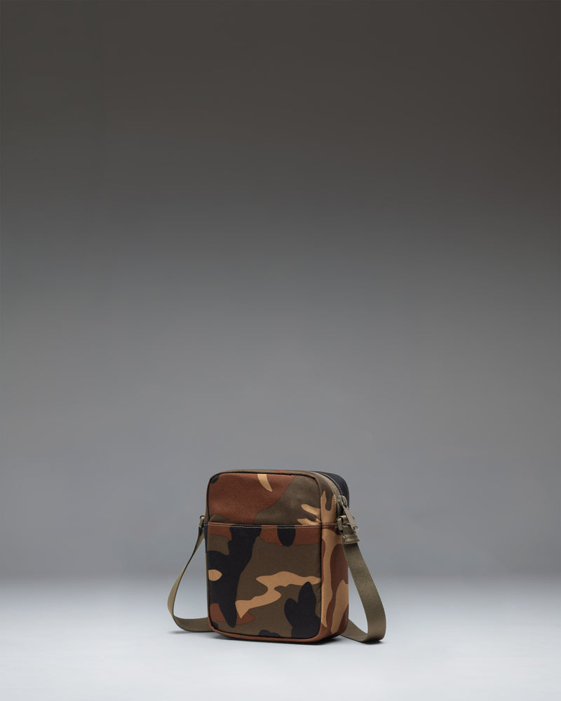 Herschel Heritage Crossbody bag in Woodland Camo with a black label, showing the front view with zipper detail.