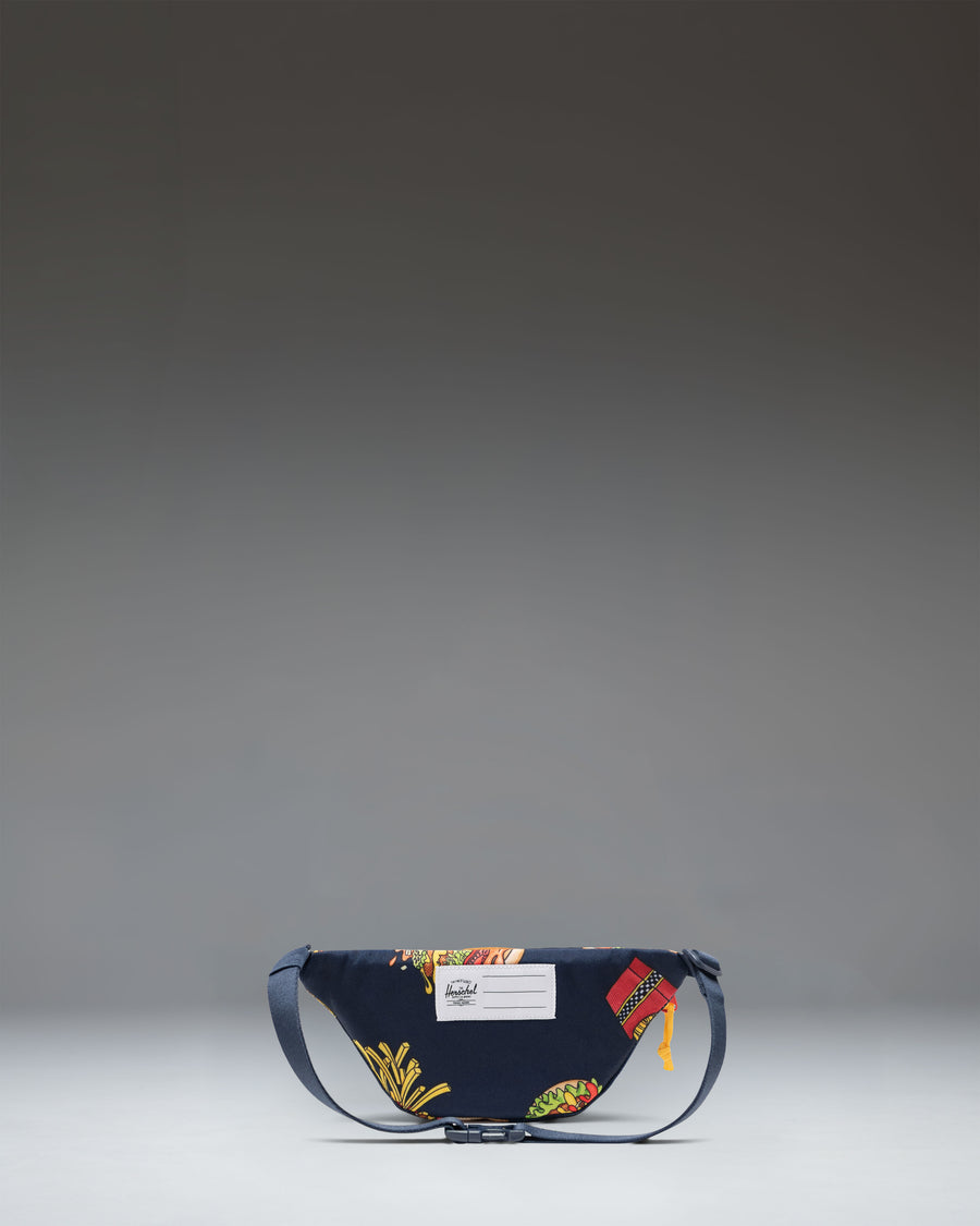 Based on the filename "11386-07201-OS_02.jpg" and the product information, this image represents the alternate view or detailed angle of the hip pack [cite: 1].

Herschel Heritage Hip Pack Little Herschel in two-tone blue and orange. Front view showing the main compartment and classic diamond accent.