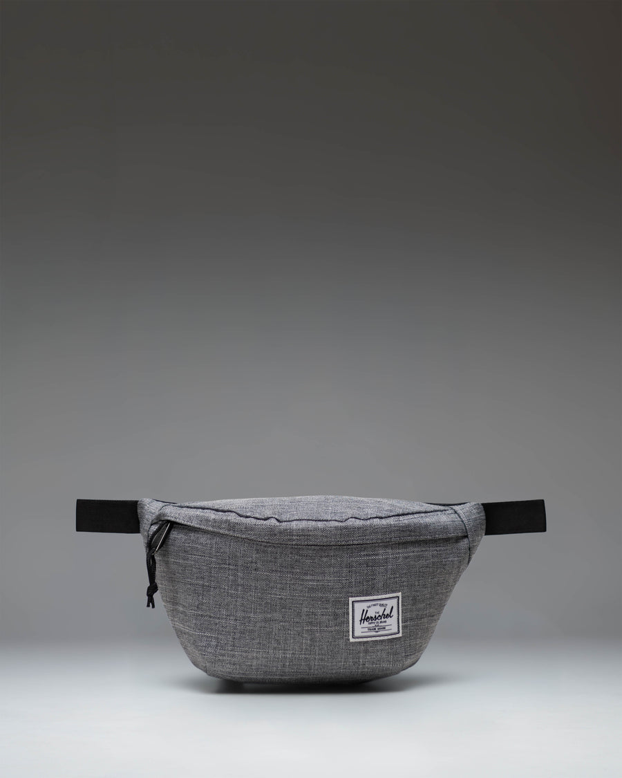 Herschel Classic Hip Pack in Raven Crosshatch grey. Front view showing main zipper compartment, adjustable strap, and classic woven label.