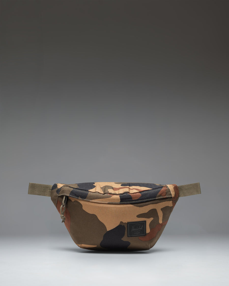 Herschel Classic Hip Pack in Woodland Camo with a black label, shown from the front against a white background.