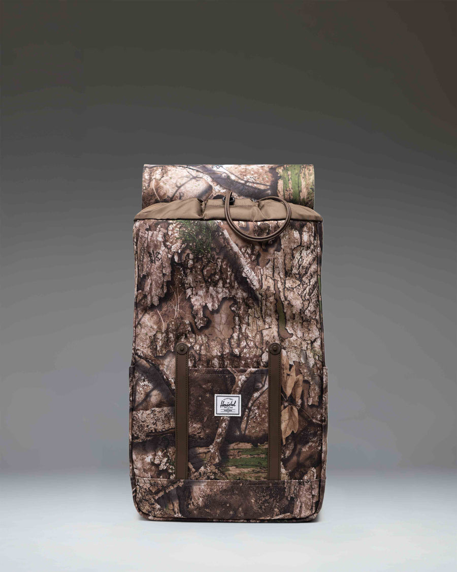 Realtree Herschel Retreat Backpack in Realtree APX Camo, showing a close-up or detailed view of the outdoor-style bag.