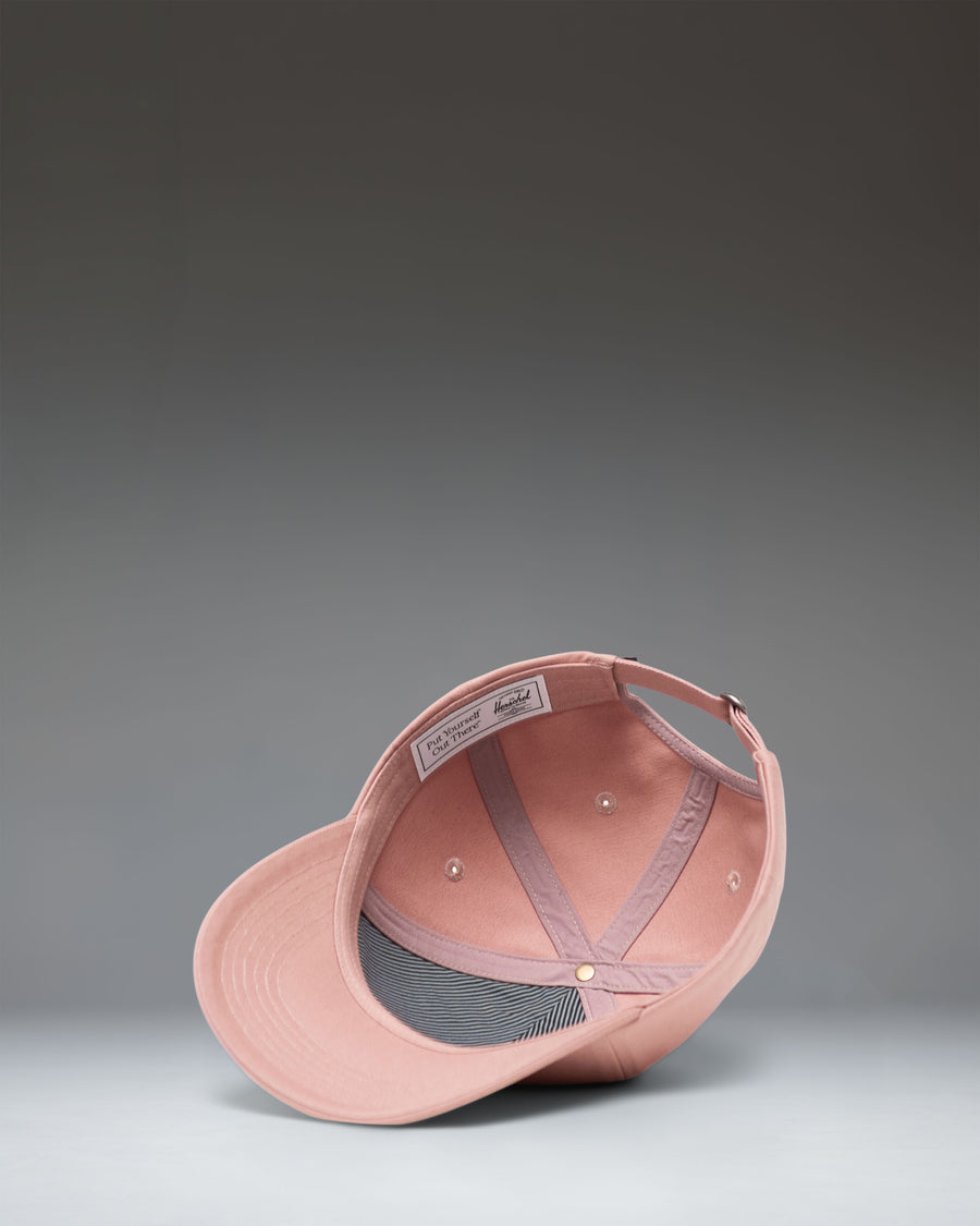 Herschel Supply Co. Sylas Classic Cap in Ash Rose, a light pink adjustable baseball hat shown from the side view.