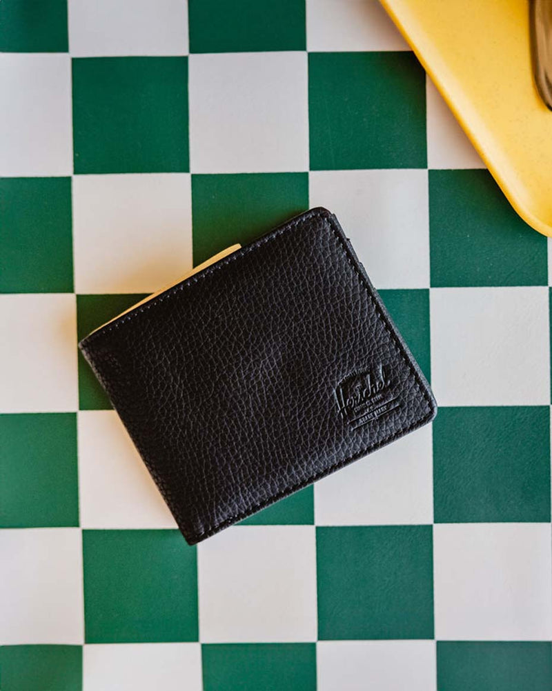 Black Herschel Roy Wallet in vegan leather, showcasing a classic bi-fold design with a minimalist aesthetic.