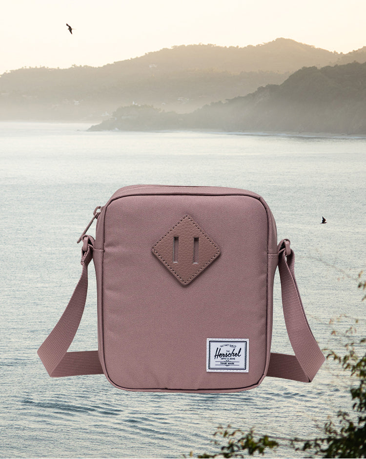 Herschel Heritage Crossbody bag in Ash Rose pink, shown from a front angle on a mobile display view.