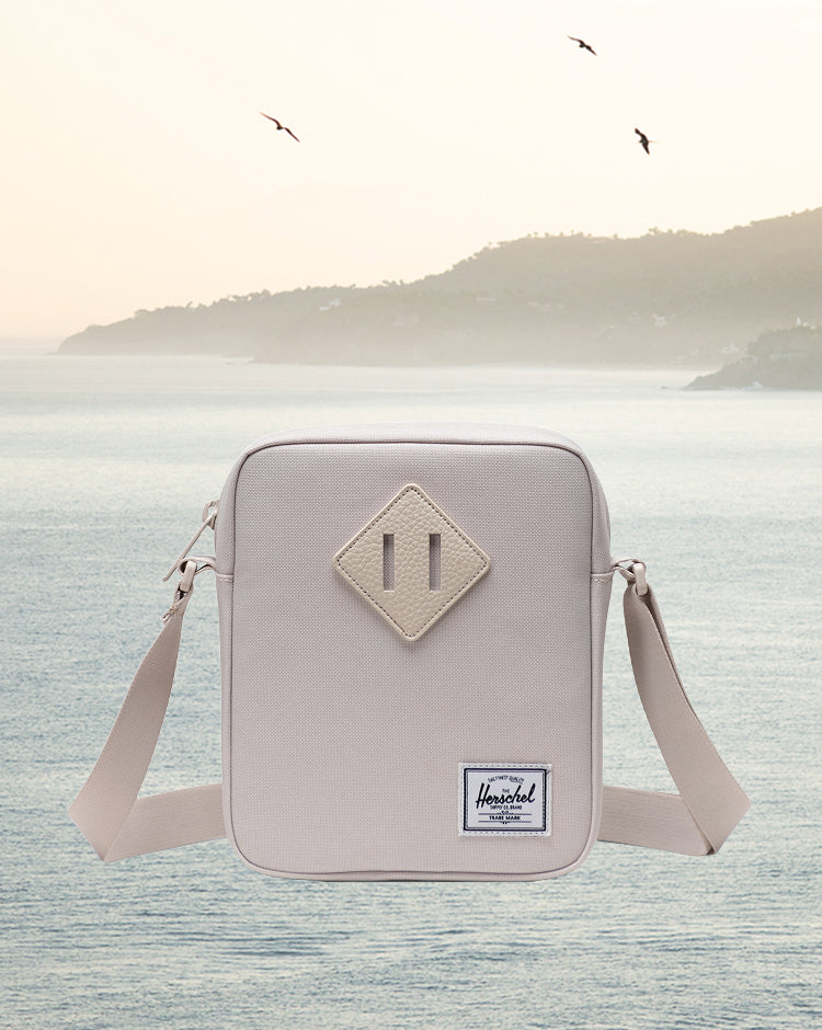 Herschel Heritage Crossbody bag in Moonbeam cream color shown on a mobile device screen.