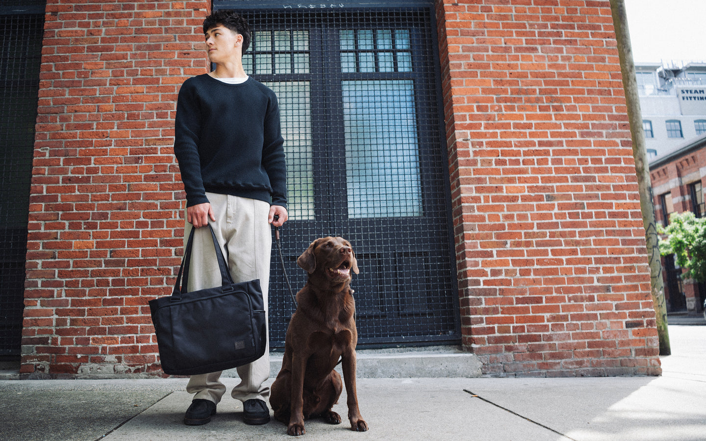 Herschel Supply Co Kaslo Tote Tech Cordura in black on a model, showcasing its modern design and storage capabilities for everyday use.