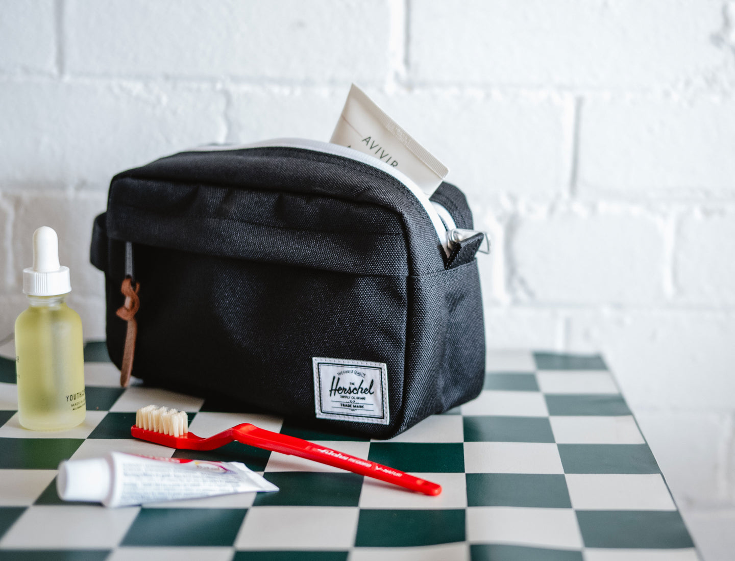 Herschel Supply Co. Chapter Small Travel Kit in black, showing the front exterior with a side handle and classic logo label.