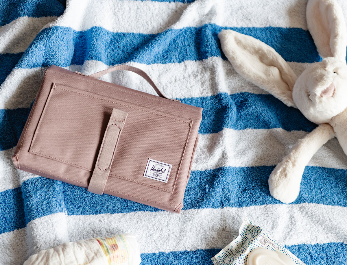 Herschel Supply Co. Sprout Change Mat in Ash Rose, unrolled and laid flat to show its clean portable design for easy diaper changes.