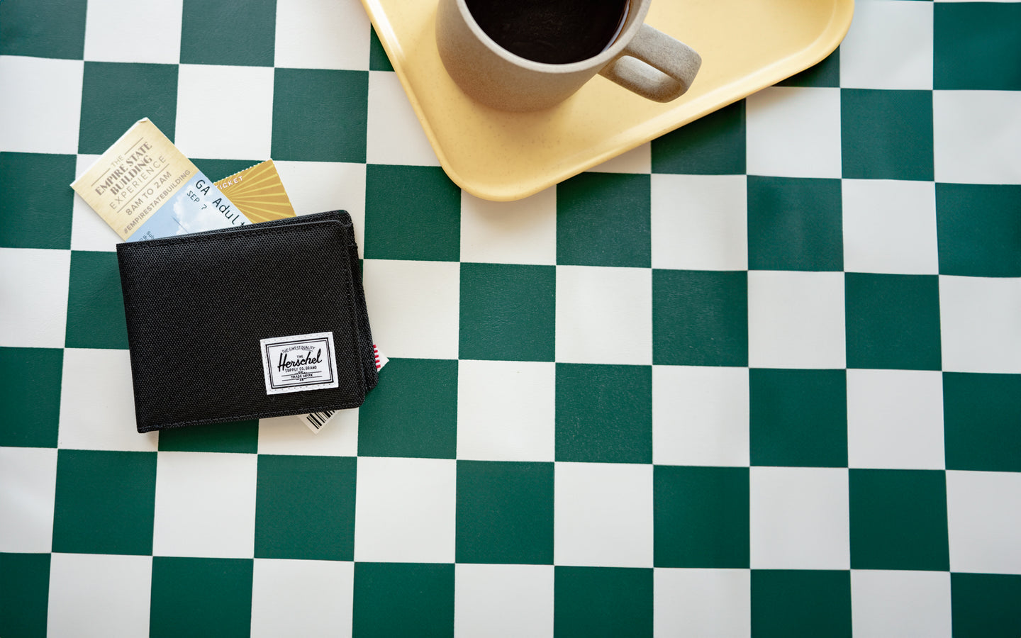 Front view of the Herschel Roy Coin Wallet in Black, featuring a classic bi-fold design with a woven label on the lower corner.