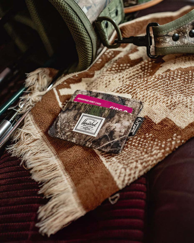 Herschel Supply Co. Charlie Cardholder in Realtree APX Camo featuring multiple card slots and a top-access storage sleeve.