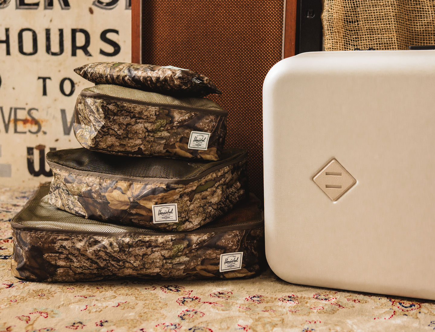 Herschel Supply Co. Realtree Kyoto Packing Cubes in Realtree APX Camo print, organized and stacked on a wooden surface.