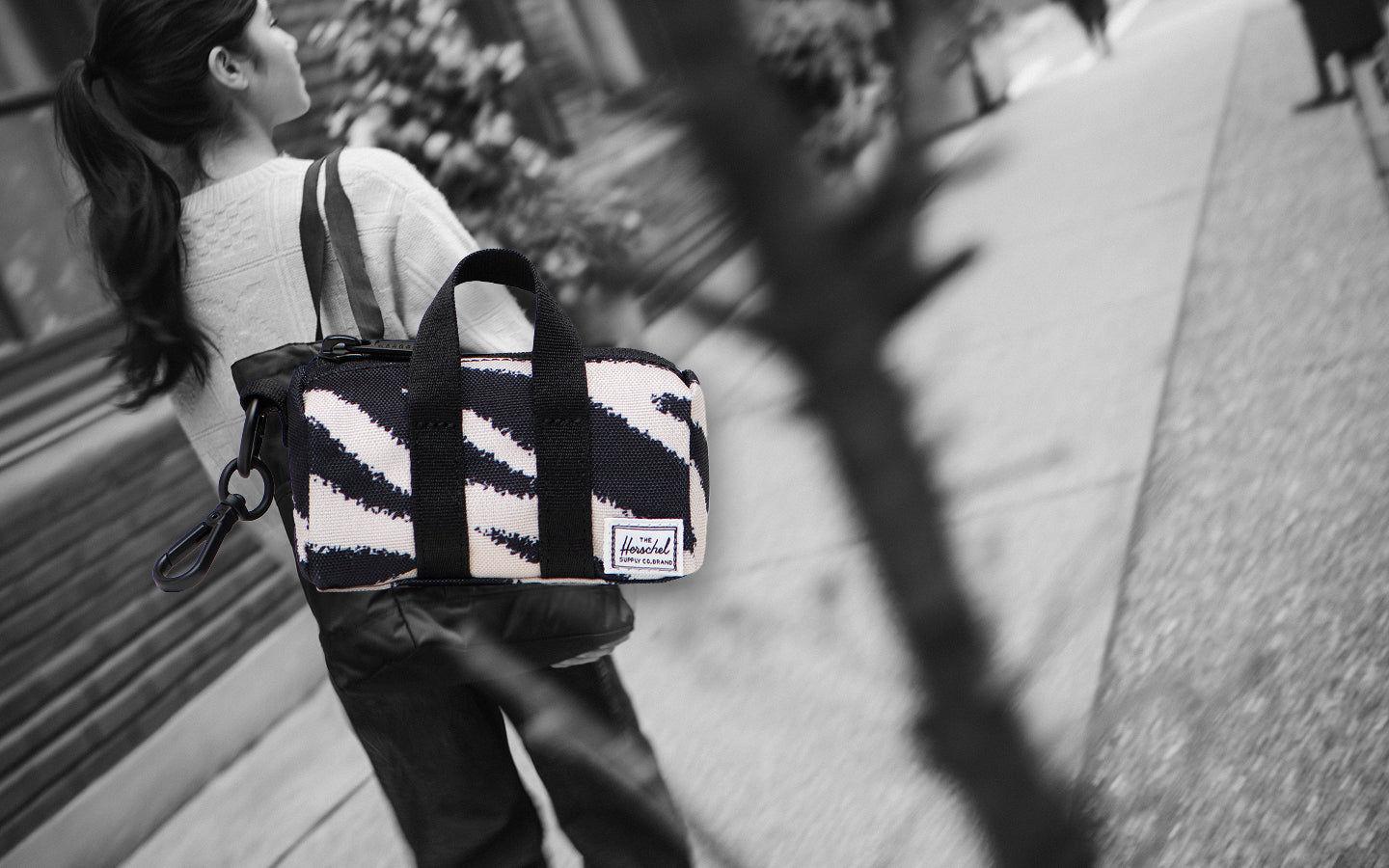 Herschel Novel Duffle Bag Charm in black and white zebra print with black carrying handles, zipper, and a convenient keychain clip.