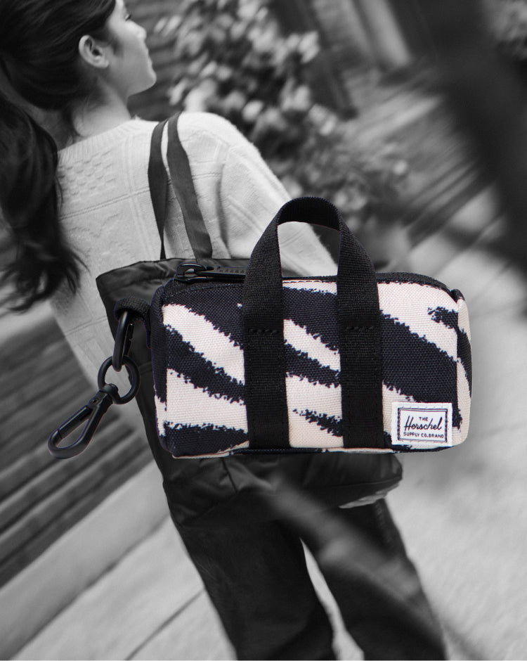 Herschel Novel Duffle Bag Charm in black and white zebra print with webbed carrying handles and a removable shoulder strap.