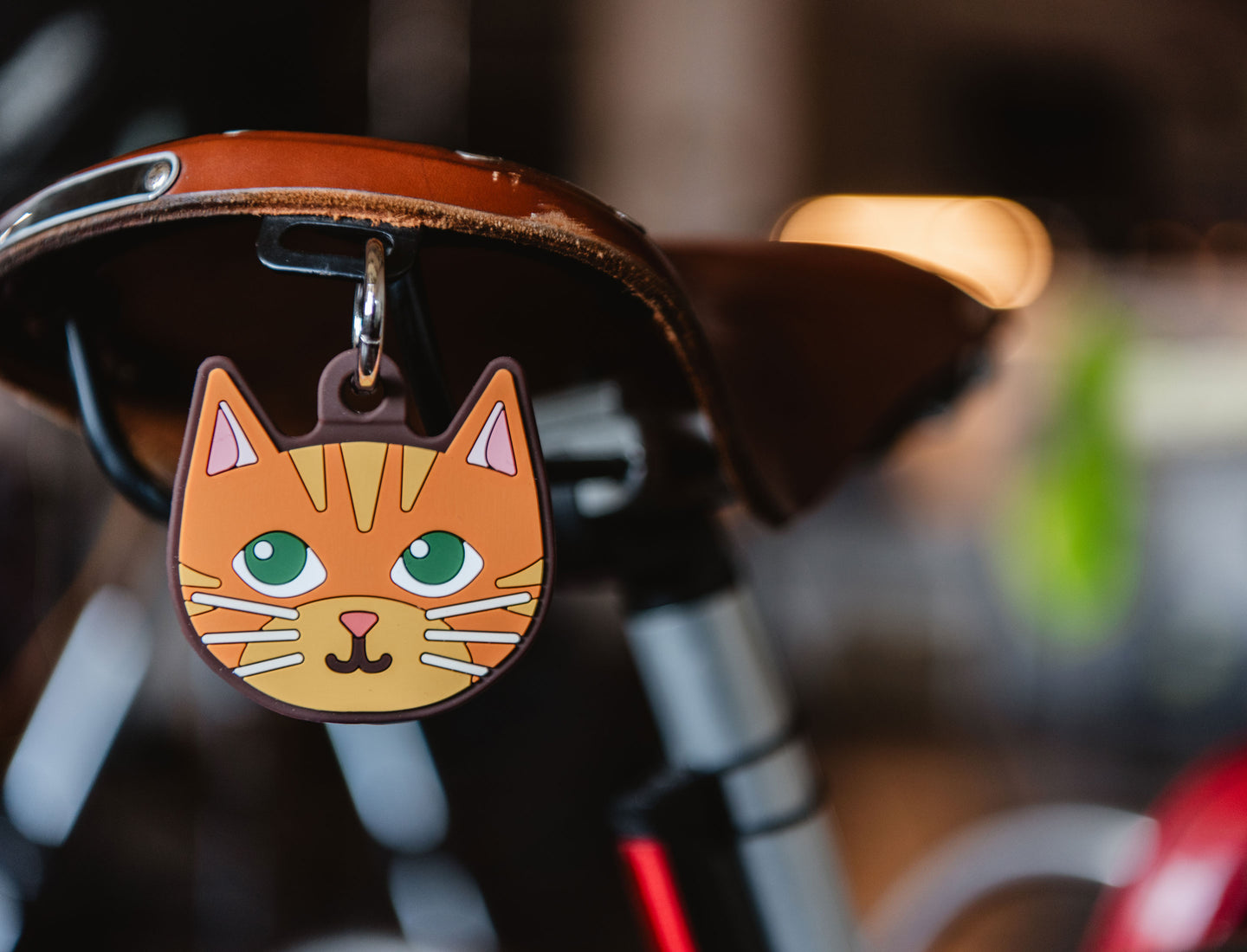Herschel Cat Bag Charm in Orange Cat featured in a lifestyle setting on a desktop background.