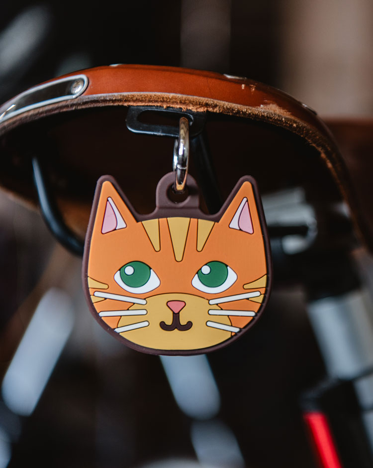 Orange tabby cat bag charm by Herschel Supply Co featuring a white muzzle and ears, attached to a silver-tone metal key ring and clip.