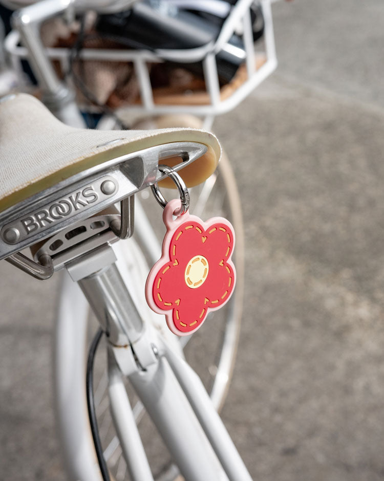 Herschel Supply Co. Pink Daisy Bag Charm featuring a pink daisy flower with a yellow center and a silver metal clip.