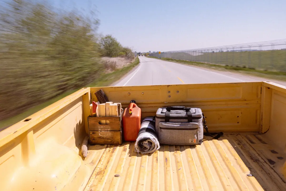 A Herschel Pop Quiz Cooler 30 Pack Insulated in the back of a pick-up truck with other supplies.
