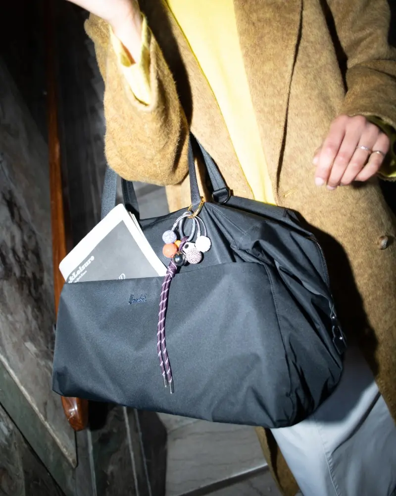 A photo of the woman holding a black maia weekender duffle over her shoulder